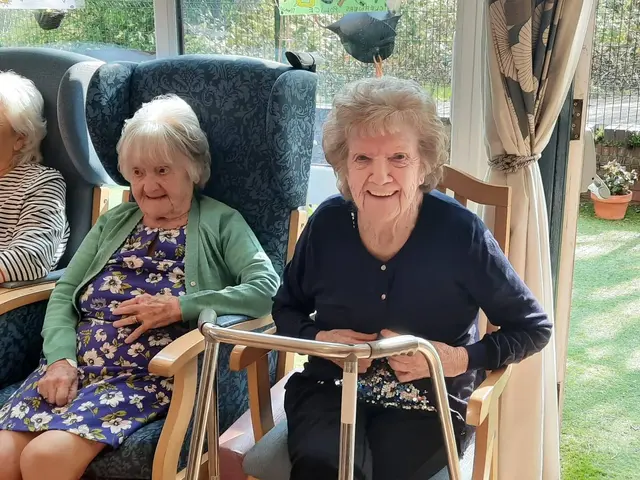 Two residents sitting side by side in the conservatory, smiling at the camera.