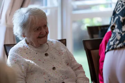 A resident smiling by the window at Aria Care Home
