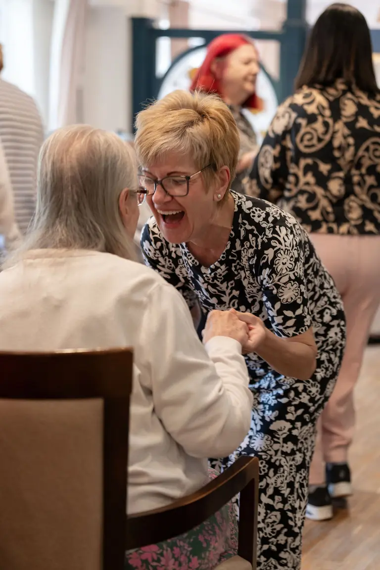A resident in a red cardigan and scarf, joyful, moving to music