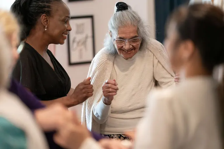 A resident dancing with two carers at Aria Care Home