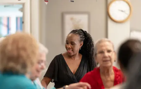 A carer smiling among residents at Aria Care Home