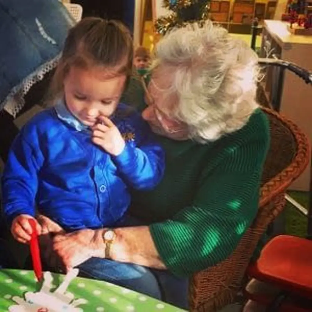 A resident and a pupil making a Christmas decoration together.